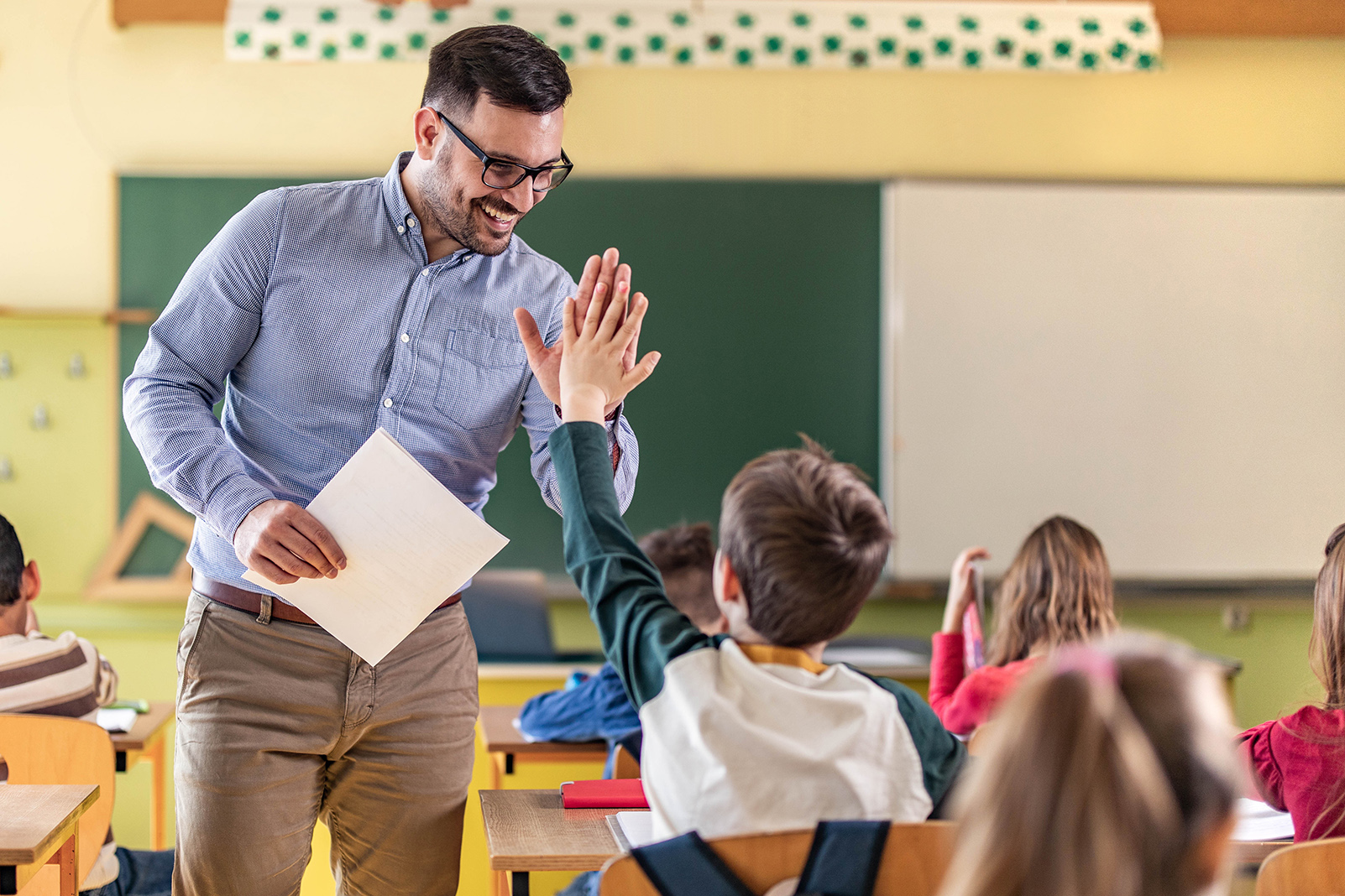 Happy teacher and schoolboy giving each other high-five on a class. New Homepage 5